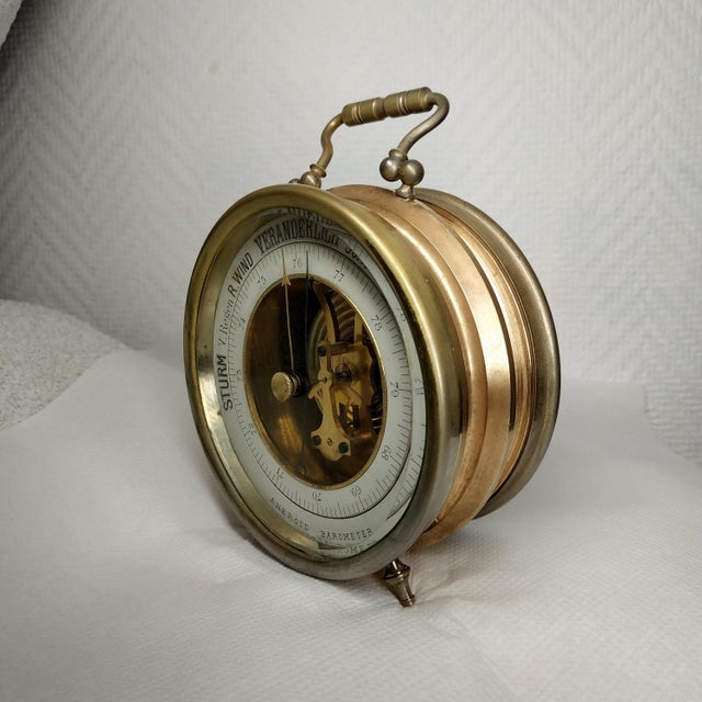 This brass barometer features a brass bezel and a dial with an open center section that reveals an exquisite gold-plated...