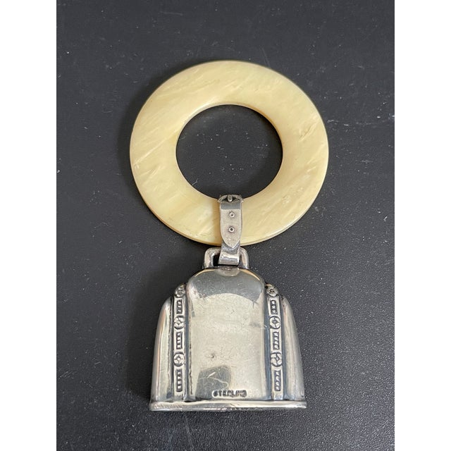 This Deco baby's teething ring rattle features a sterling silver bell accented with geometric designs at the sides and a...