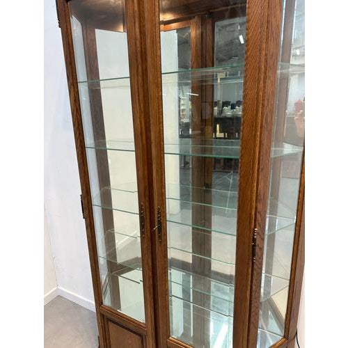 Elegant vintage display cabinet crafted in solid oak, featuring a warm natural wood tone and classic architectural lines....