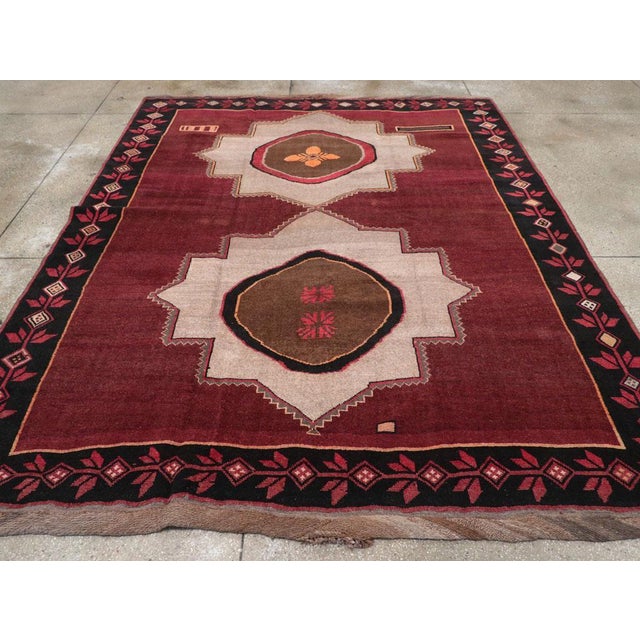 This wool pile carpet, woven with symmetric knots on a wool foundation, is nearly square in shape. It features two...