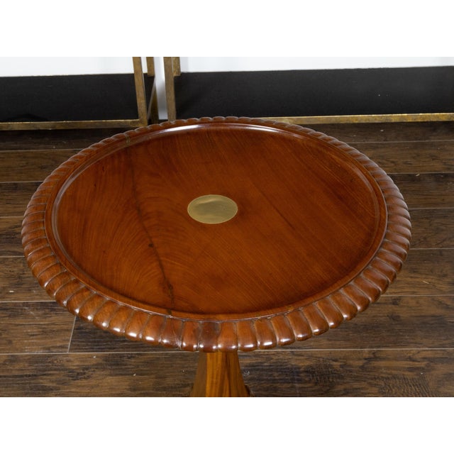 An English mahogany guéridon pedestal side table from the 19th century with brass inlay, gadroon motifs and carved griffin...
