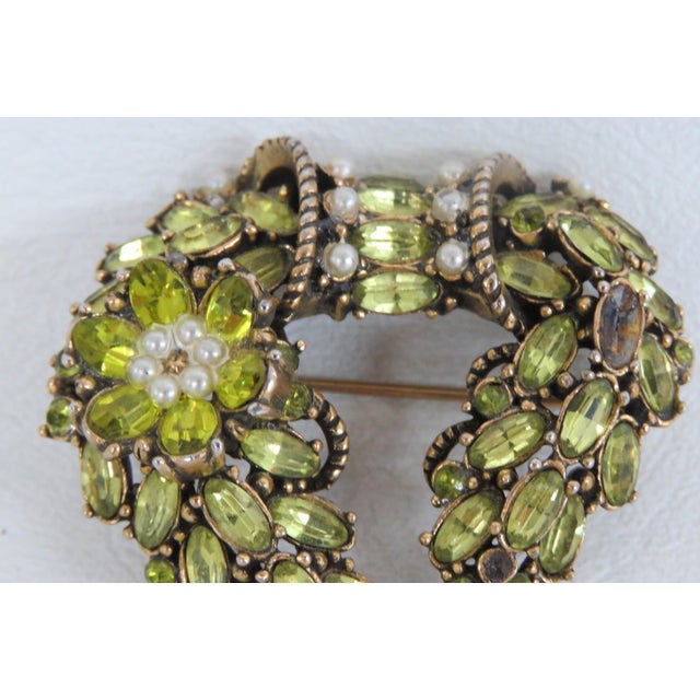 This gorgeous brooch pin is made of metal, rhinestones, and faux seed pearls. It is marked on the back as having been made...