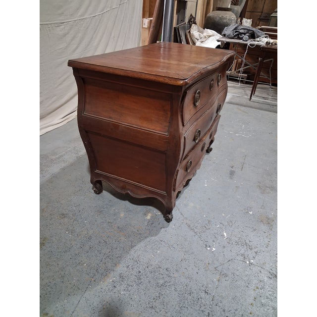 A handsome late 18th-century French Provincial walnut commode featuring elegant bombé sides, serpentine drawer fronts, and...