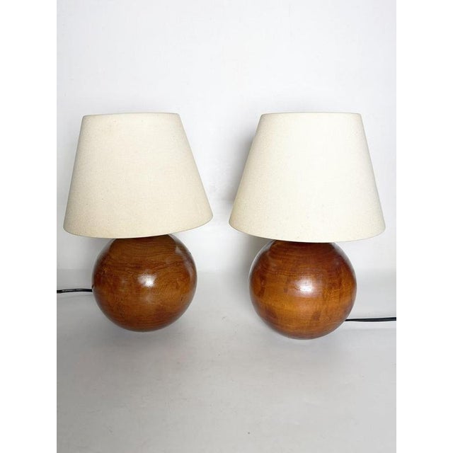 Pair of French wooden table lamps dating from the 1970s, featuring beautifully rounded spherical bases with a warm brown...