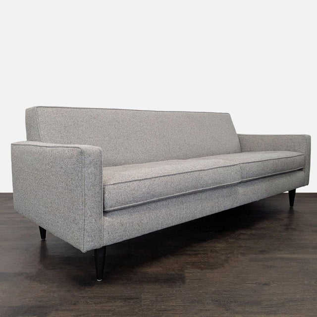 This Room and Board 3-seat sofa features a simple, modern design with clean lines and a soft gray fabric. The sofa sits on...