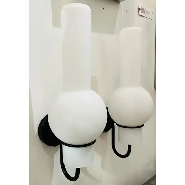 A wonderful pair of sleek black and white wall lights with tall glass shades circa 1960 by Raak. Original label. Rewired.