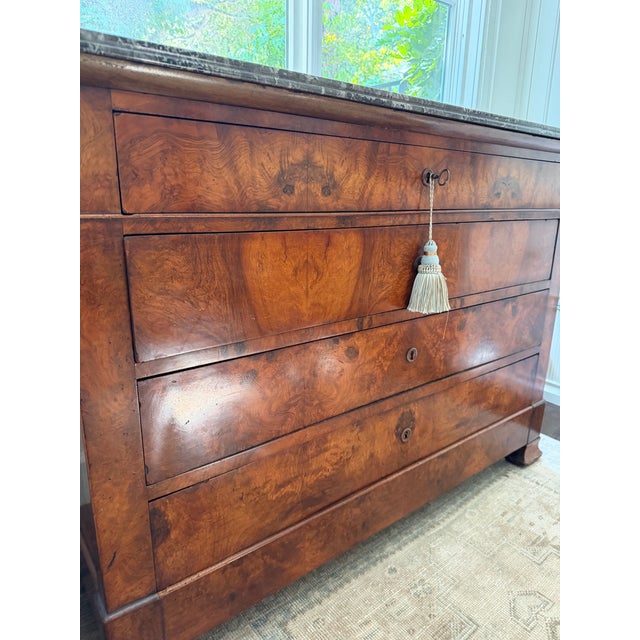 Louis Philippe console chest or commode from France, with a black marble top and a veneer of burled walnut. A tasseled key...