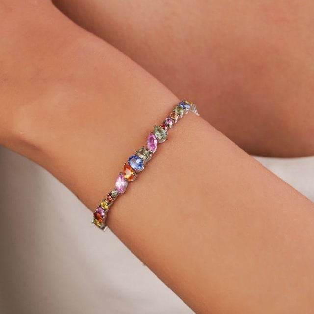This tennis bracelet features 10.97 carats of natural mixed shape natural multicolor sapphires, set in 18K white gold....