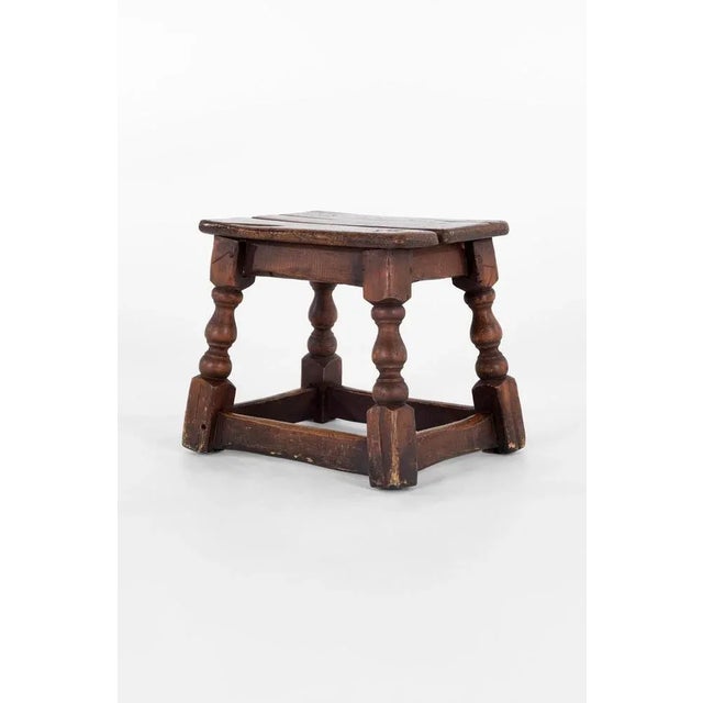 A charming 18th-century low oak stool. The characterful two-plank top is raised upon four sweeping turned legs finishing...