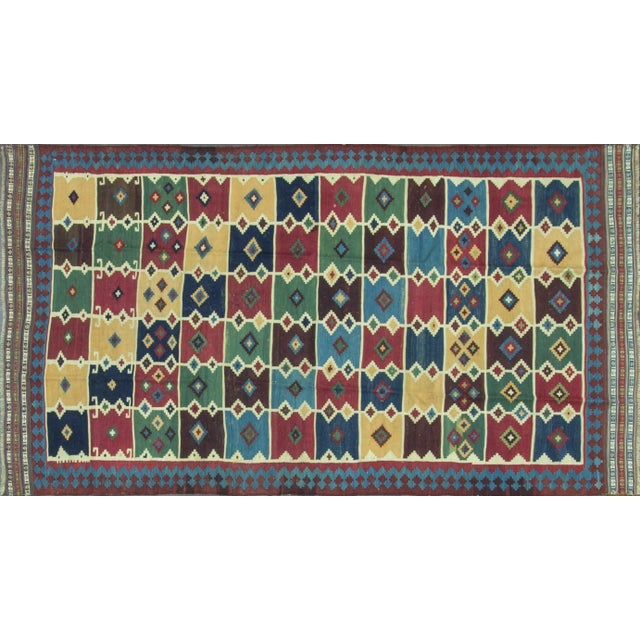The polychrome field with horizontal bands of mustard, midnight blue, powder blue, green, and ivory rectangular motifs. In...