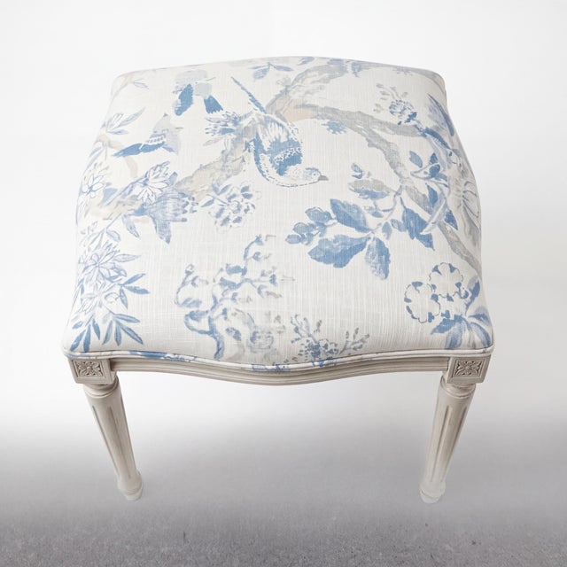 This is a pair of French Louis XVI style upholstered ottomans newly upholstered in a blue and white linen. The linen has a...
