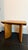 A shape-driven end table made from thick-cut oak veneer features overscale proportions and half-moon shaping in a warm...