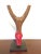 A colorful slingshot from the Baule people. Vibrant red handle is carved with opposing animal heads. Displayed on a custom...