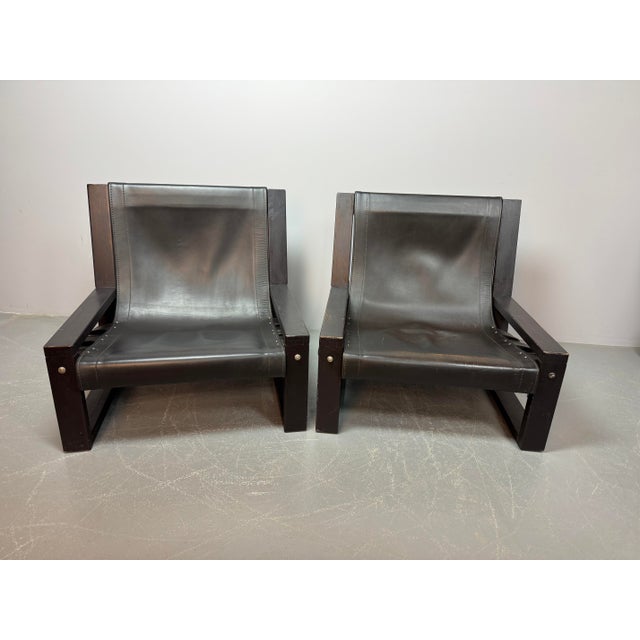 Set of two brutalist lounge chairs designed by Sonja Wasseur. Featuring black saddle leather upholstery and a black-...