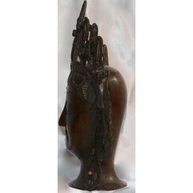 This is a Thai bronze head figurine with an ornate open work headdress. She has elongated ears with decorative earrings...