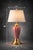 A classic Hollywood Regency table lamp featuring a fluted pink ceramic body paired with polished brass accents and a large...