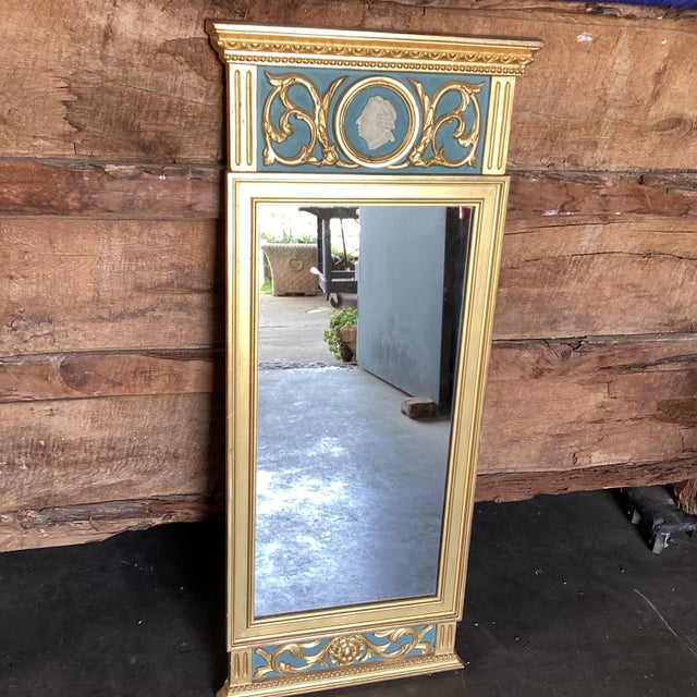 A Swedish neoclassical style gilded mirror with cameo and "rais-de-coeur," beaded molding and fluted elements. This...