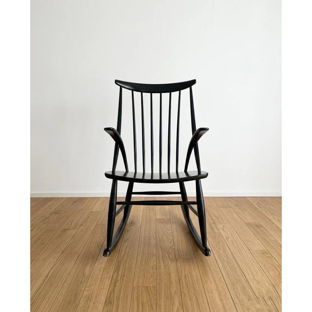 Rocking chair, designed by Illum Wikkelsø, Danish, 1950s. Black lacquered wood frame with a high backrest featuring turned...