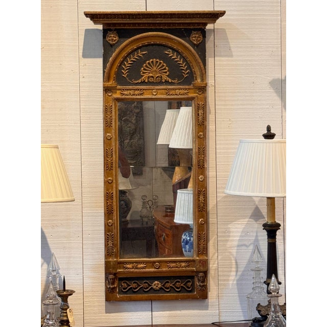 A French Empire pier mirror, the projecting cornice carved with gadrooned and egg and dart moldings above a black ground...
