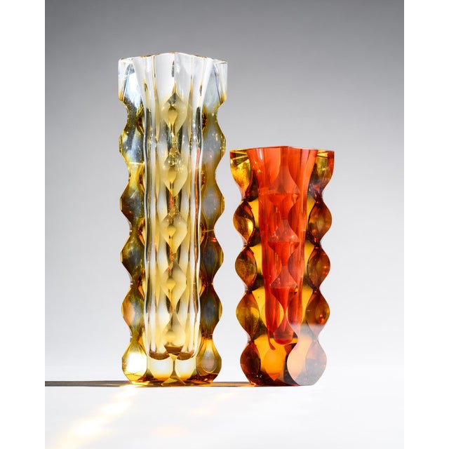 A luminous duo of Exbor art glass vases by Oldřich Lipa, combining deeply cut wave forms with rich amber, yellow, and ruby...