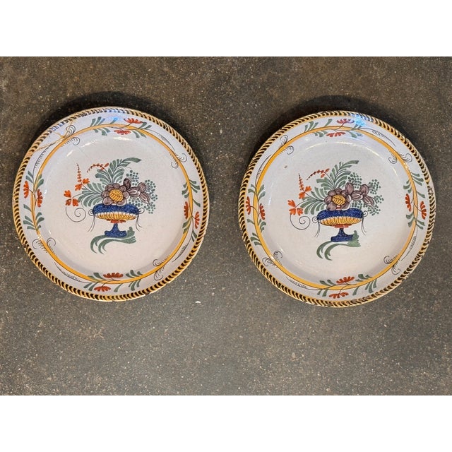 A well-matched pair of Delft polychrome plates, each painted with a central floral urn in blue, green, orange, and...