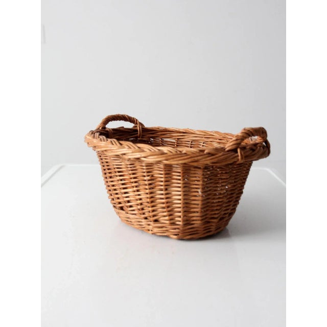 This vintage woven harvest basket adds a rustic touch to any home. Woven in an oval shape with braided detailing, it has...