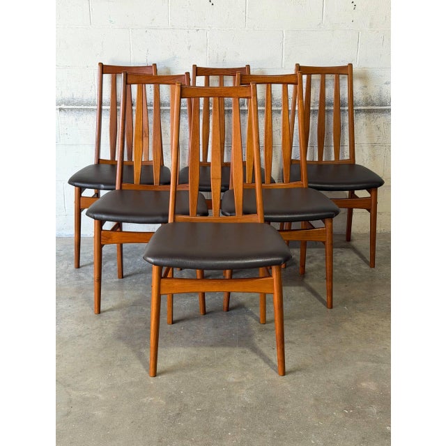 This set of six dining chairs features tall backrests composed of vertical slats. The gently curved frames offer a...