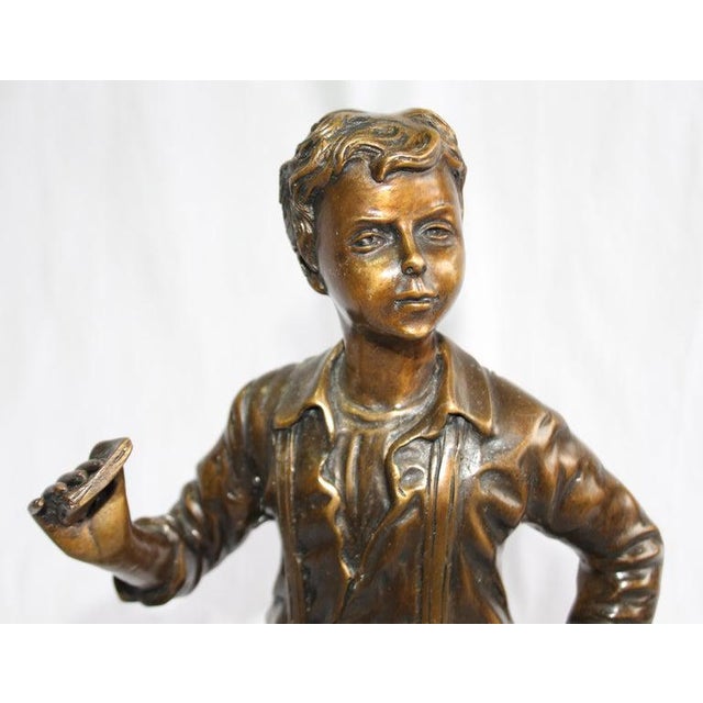 A bronze figure of a boy. French, mid to early 20th century. Mid brown patination. Shown standing wearing braces and...
