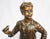 A bronze figure of a boy. French, mid to early 20th century. Mid brown patination. Shown standing wearing braces and...
