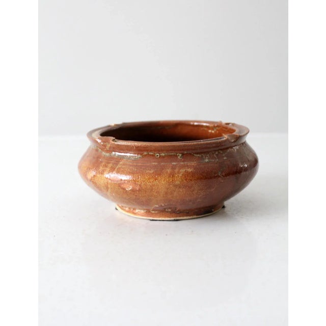 This handcrafted vintage pottery bowl, with its warm glaze and four distinctive rim notches, offers a touch of rustic...