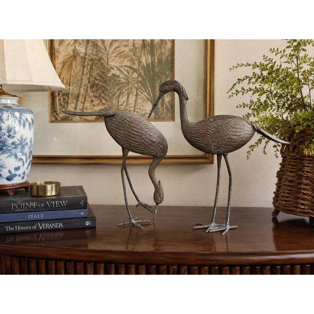 A charming vintage pair of metal crane sculptures featuring beautifully detailed plumage, elegant proportions, and...