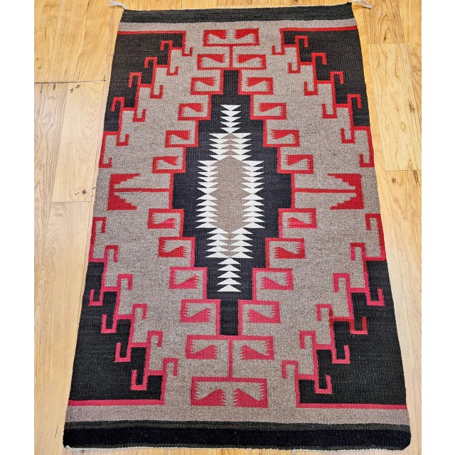 This finely handwoven vintage Navajo rug was crafted in the mid-20th century by Native American weavers of the Southwest...