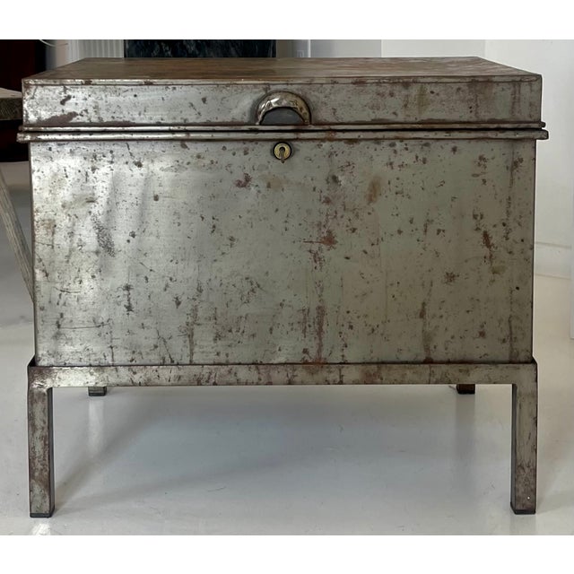 A distinctive antique industrial steel trunk/chest raised on a simple metal stand, retaining its original aged finish and...