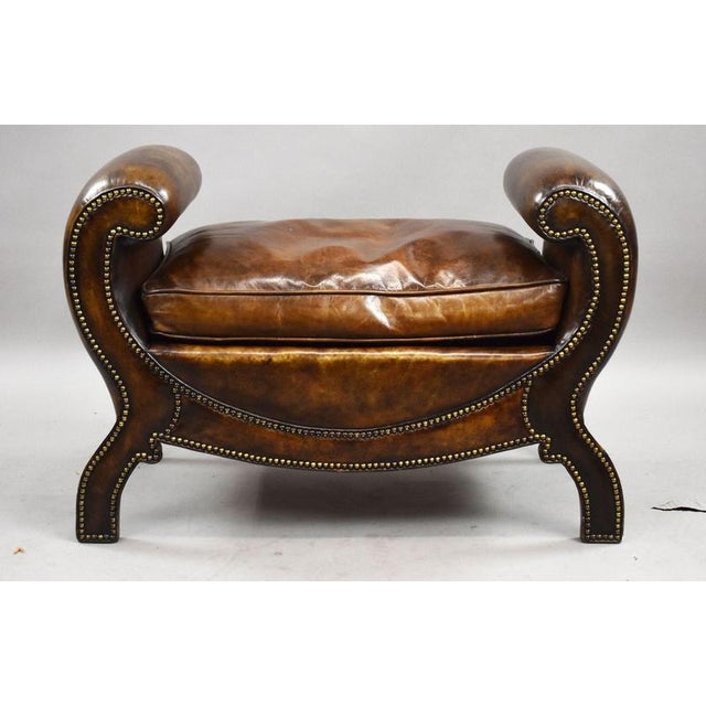 A beautifully made Regency style leather window bench, dating from circa 1920, featuring bold scroll arms and rich hand-...