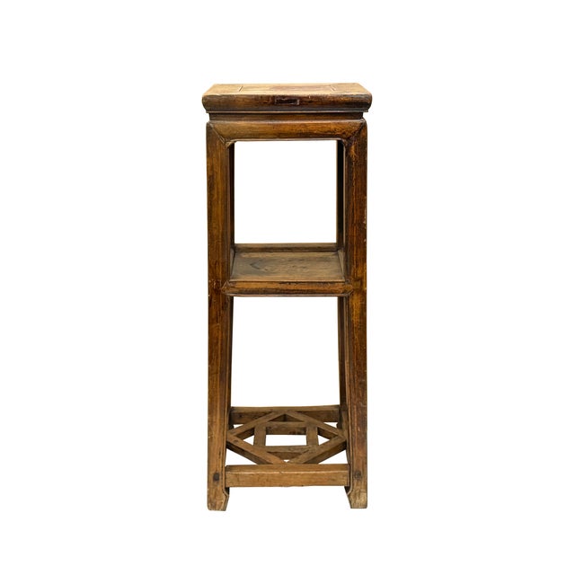 This tall, square display stand is crafted from wood with a weathered, honey-brown patina that highlights its rustic...