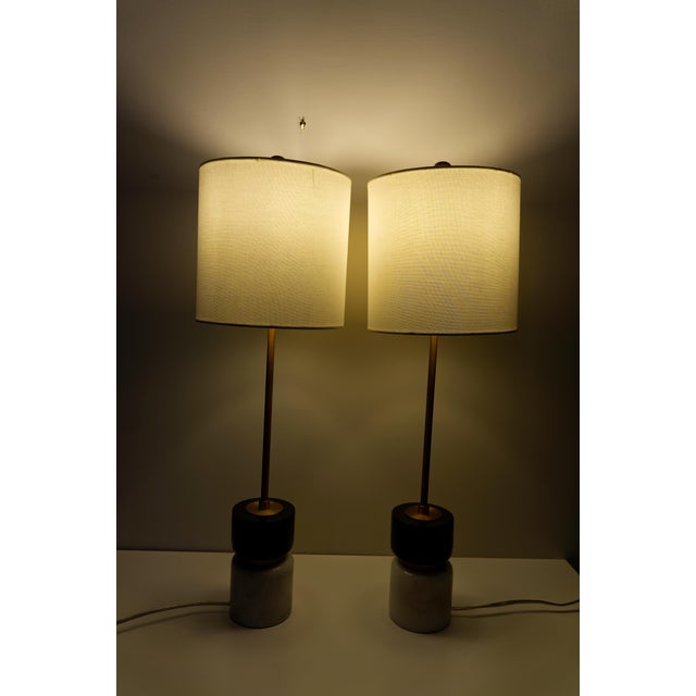 A sophisticated pair of contemporary table lamps crafted from striking black and white stone with brass finish fittings...