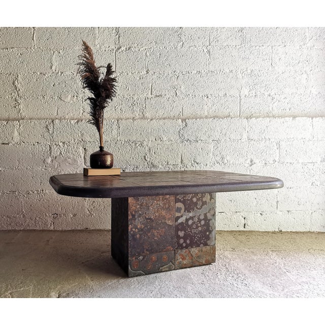 This brutalist coffee table, made of slate/natural stone and delicate brass elements, dates from the 1970s and perfectly...