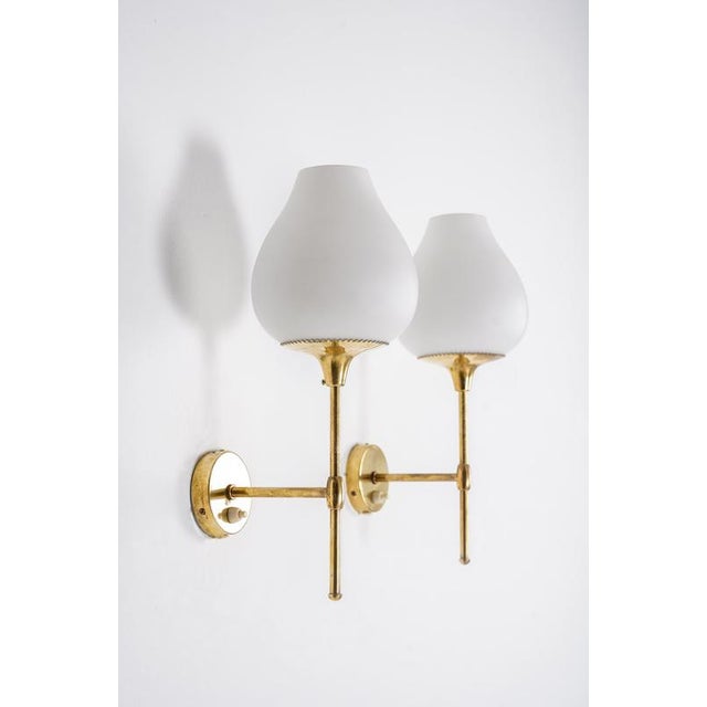 Elegant swedish mid-century wall lights in solid brass with opaline glass shades. The design is slender and well-balanced,...