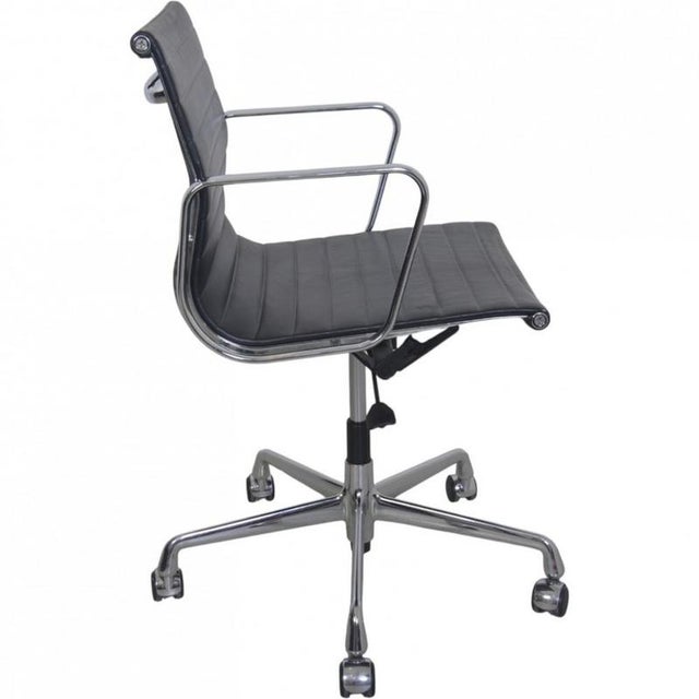 Charles Eames office chair model Ea-117, upholstered in black leather, and with chrome armrests and frame. The chair is...