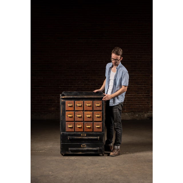 An antique wooden cabinet featuring 14 pull drawers, supported by rolling caster wheels. The majority of the cabinet...