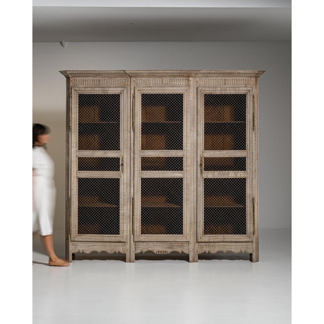 Cerused oak mesh-front cabinet in Weathered Whitewash. Its weathered whitewash finish sets off woven metal mesh door...