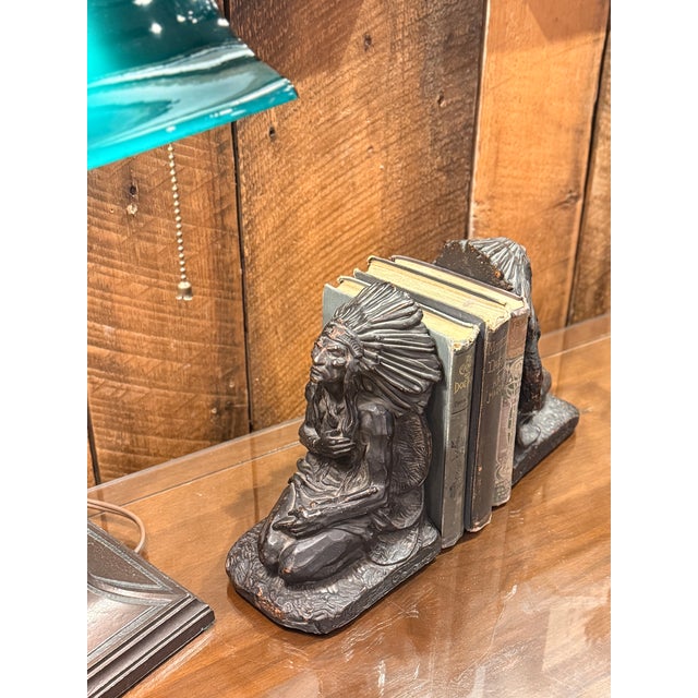 A powerful and highly decorative pair of 1920s figural bookends attributed to J.L. Lambert, featuring a seated Native...