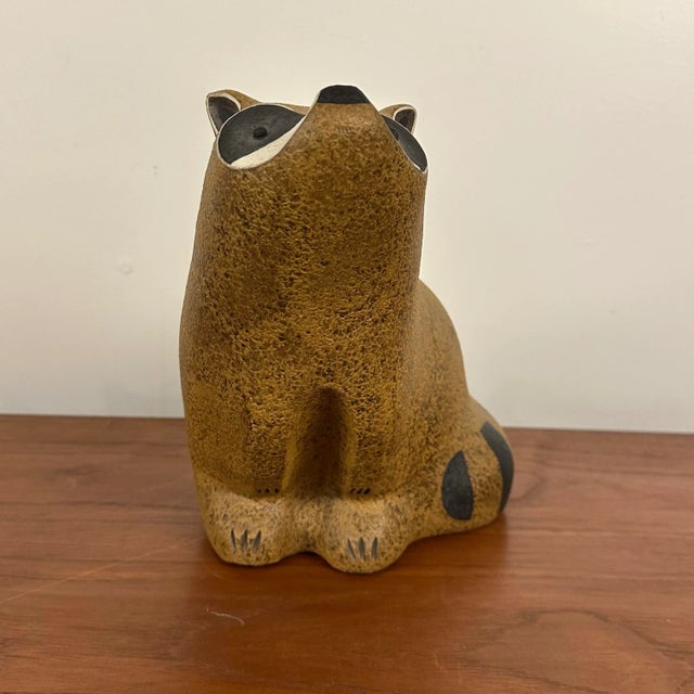 This is a limited edition stoneware raccoon figurine by John Seymour. It is number 63/500. The raccoon is in a sitting...