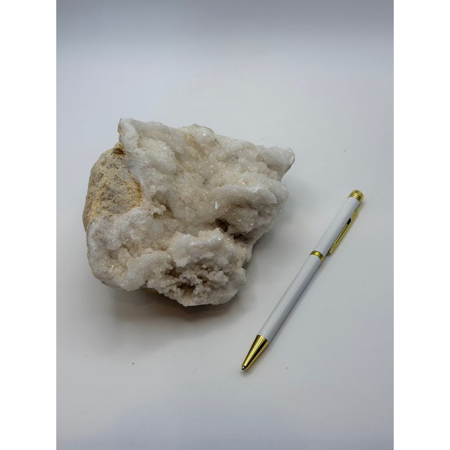 Sculptural natural white quartz crystal cluster featuring sparkling crystalline formations over a raw stone matrix. Its...