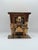 A vintage copper-toned music box featuring a stylized piano player seated at a grand piano, rendered in sculptural metal....