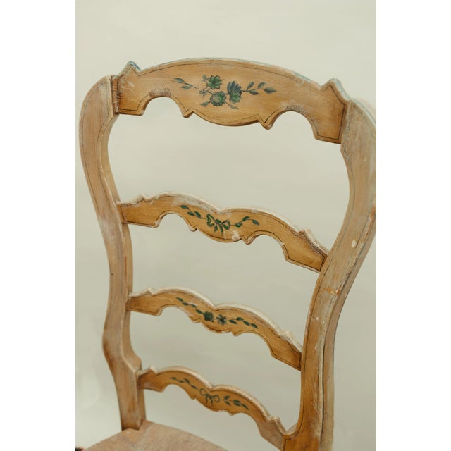 A charming set of three antique ladder-back chairs, worn beautifully by time and use. Each chair features a softly curved...