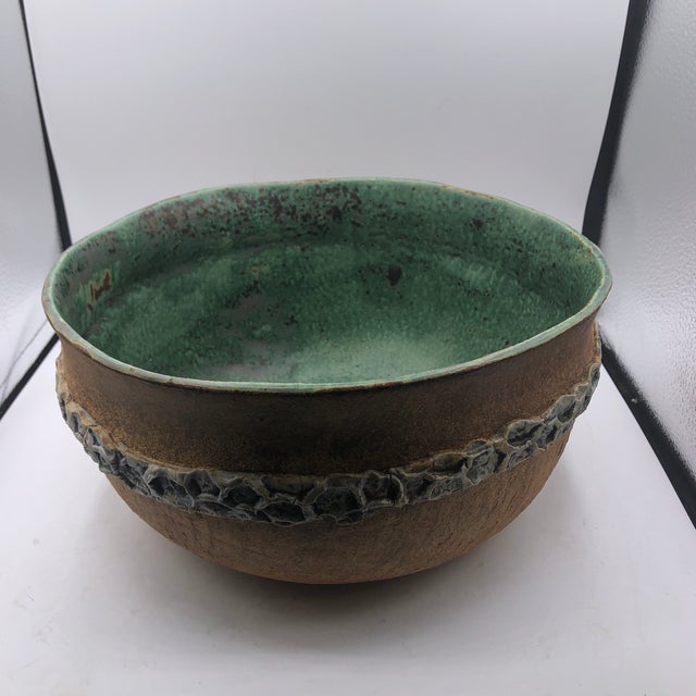 Large brown pottery bowl with a green interior and a blue band that wraps around the outside. Signed EW on bottom
