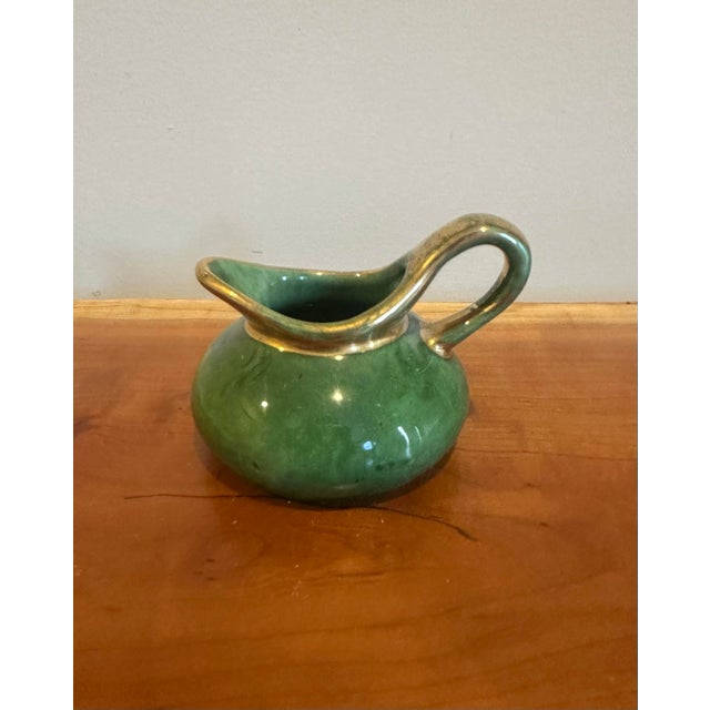 A beautifully rounded ceramic creamer finished in a rich emerald green glaze with subtle tonal variation. The sculptural...