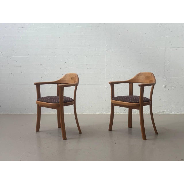 Characterful vintage armchairs from design + handwerk, crafted from warm-toned wood and featuring the original...