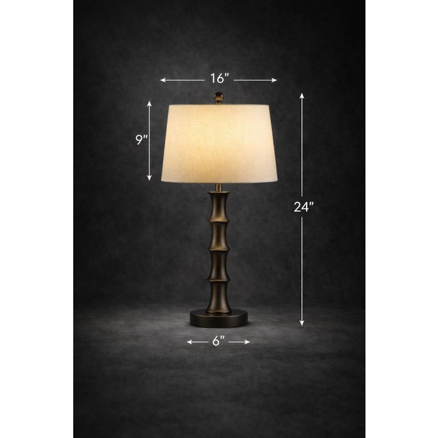 A striking pair of sculptural table lamps in a rich dark bronze finish, featuring a bold segmented column form and warm...